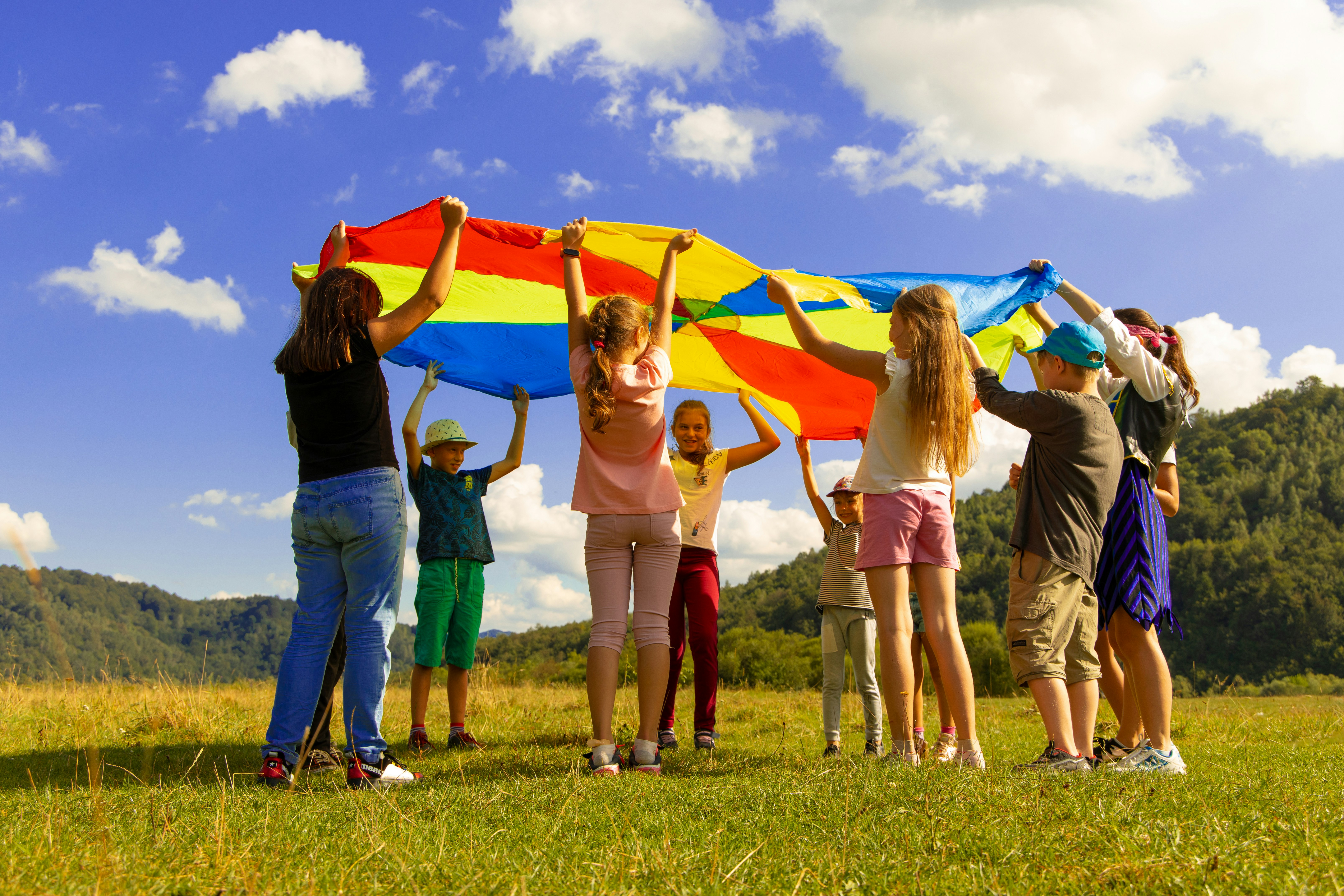 children holding coloful parachute over their heads